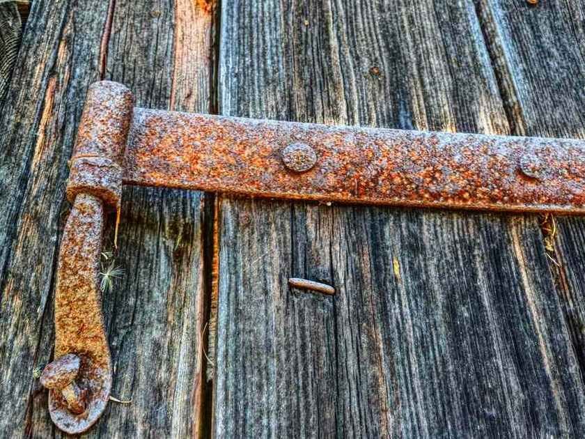 Hingé rouillé fixé sur planches de bois usées, aucune activité visible