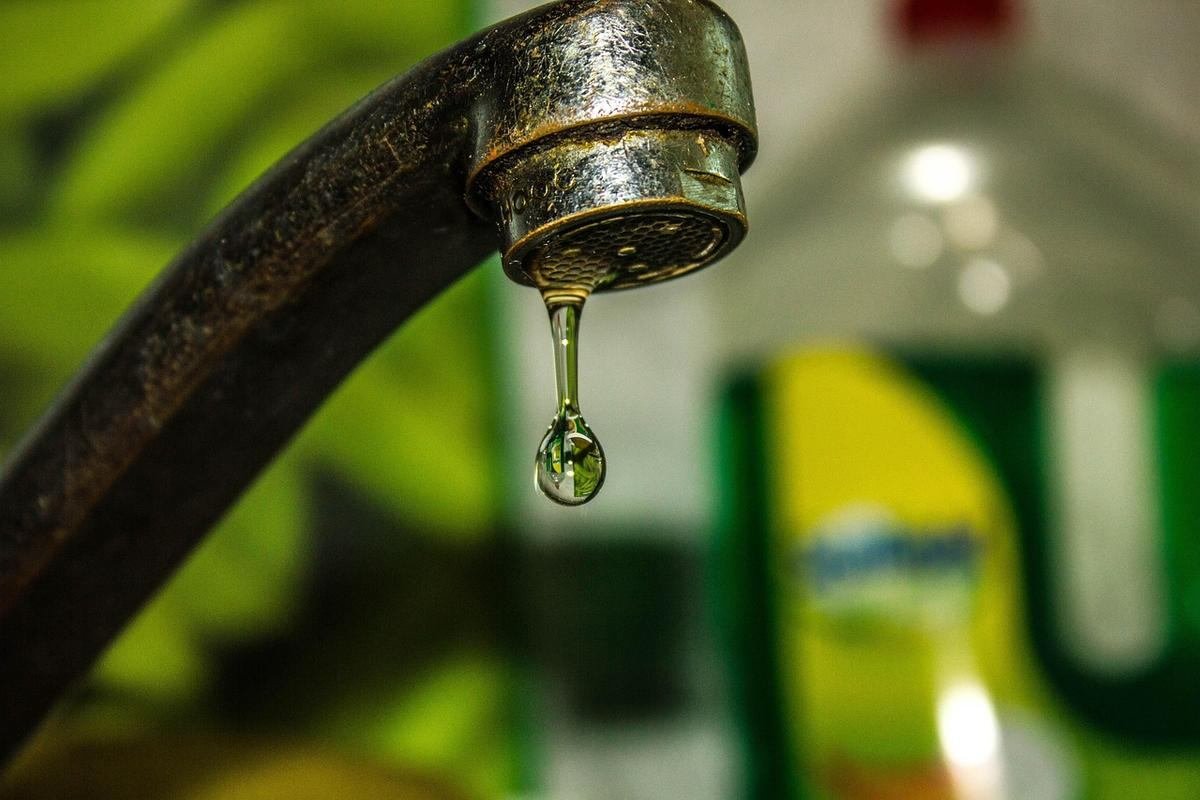 Une goutte d'eau tombe du robinet rouillé dans une cuisine