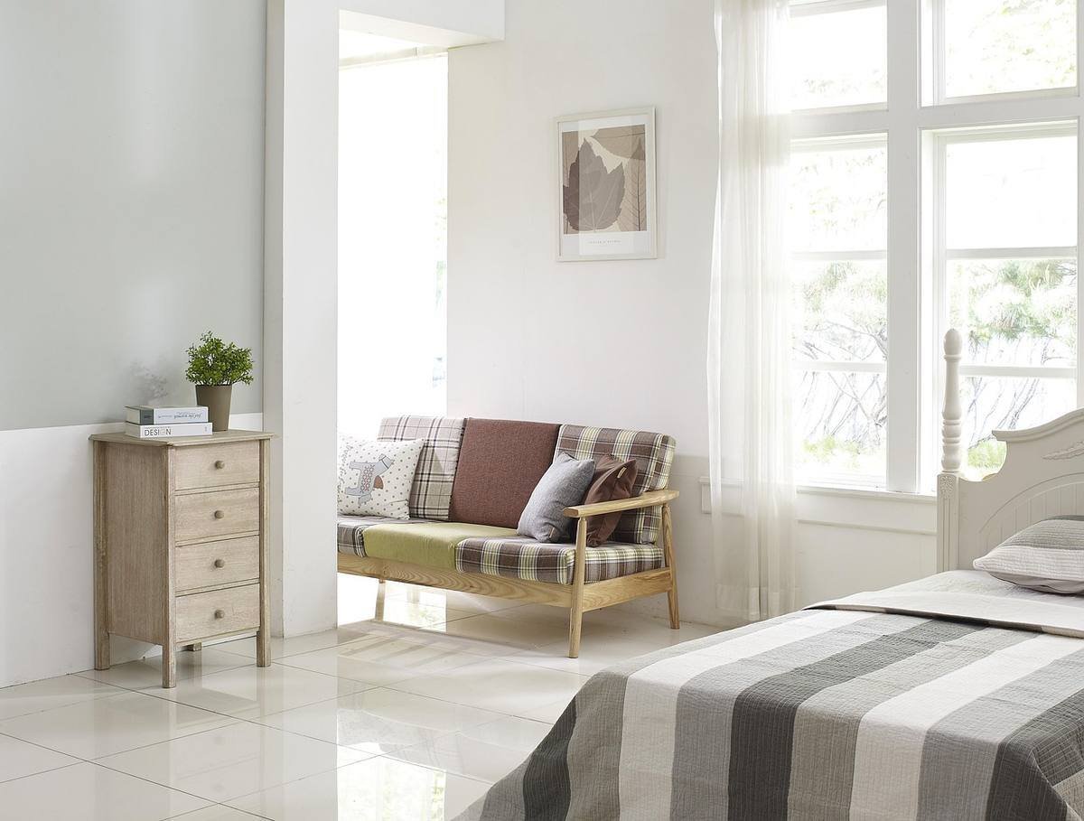 Chambre spacieuse avec canapé en bois, lit rayé et grandes fenêtres claires Chambre spacieuse avec canapé en bois, lit rayé et grandes fenêtres claires