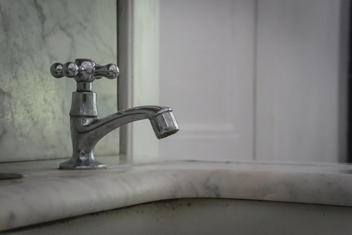 Un robinet à poignée croisée sur un lavabo en marbre Un robinet à poignée croisée sur un lavabo en marbre