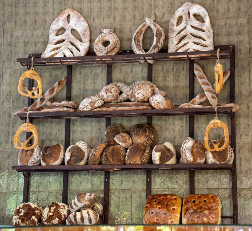 Étagère en bois remplie de pains, bagels et ustensiles de boulangerie Étagère en bois remplie de pains, bagels et ustensiles de boulangerie