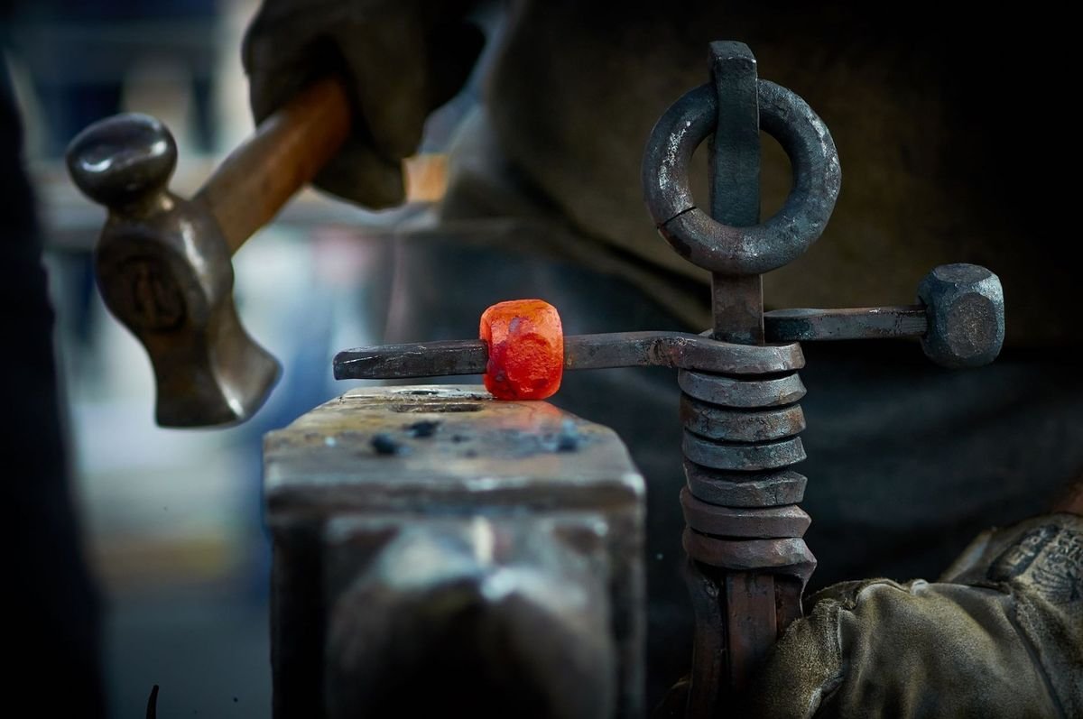 Marteau sur enclume, métal rouge sur tige, artisan métallurgique au travail Marteau sur enclume, métal rouge sur tige, artisan métallurgique au travail